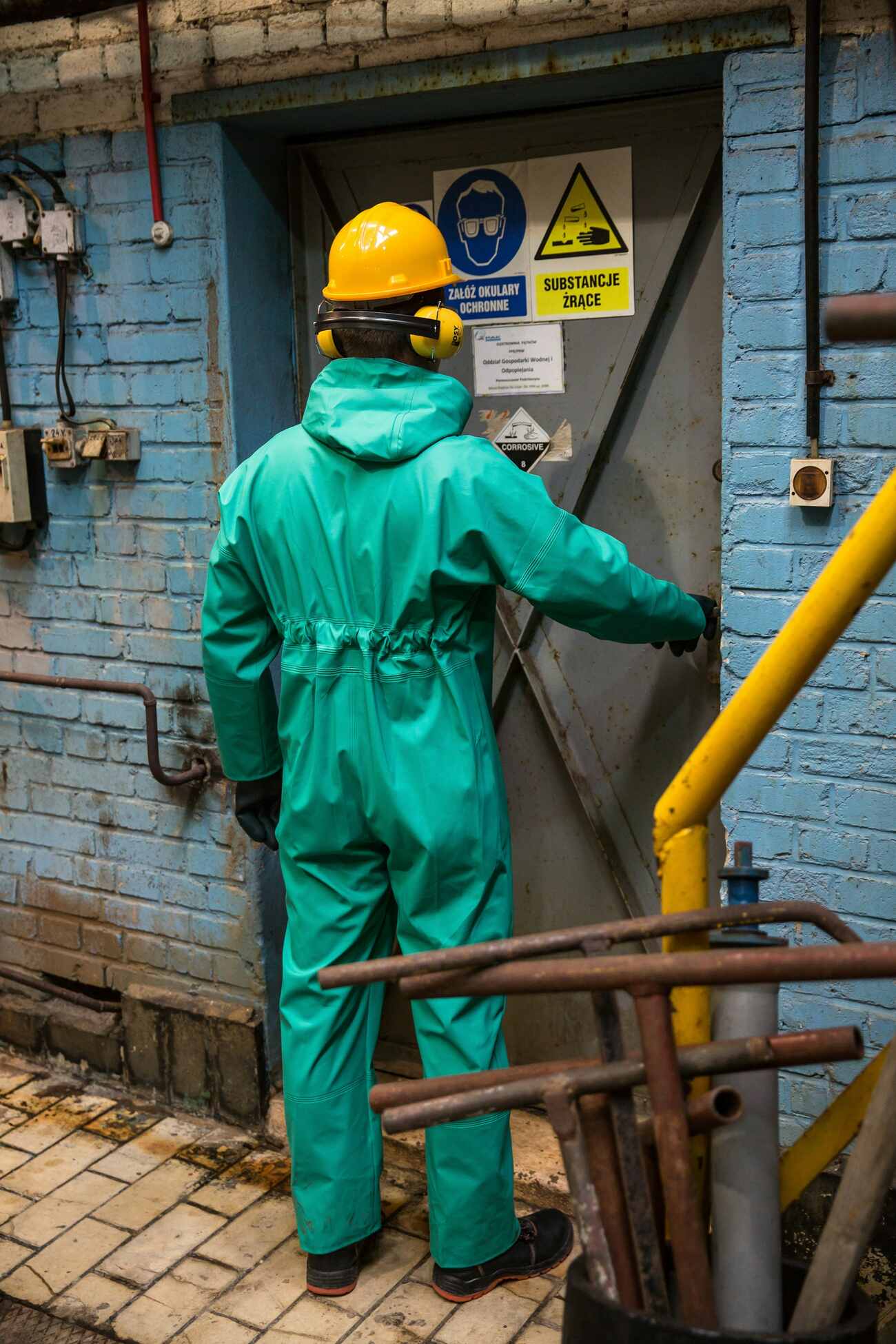 A man in a safety suit standing in front of a steel door