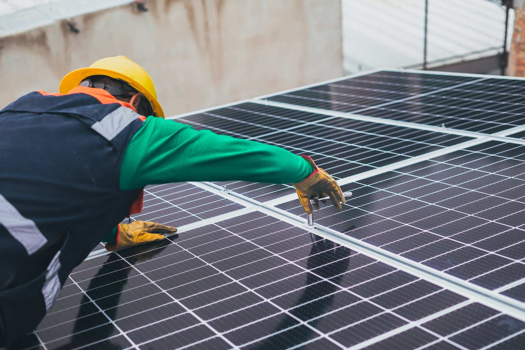 A man with safety suit and hat installing solar panels